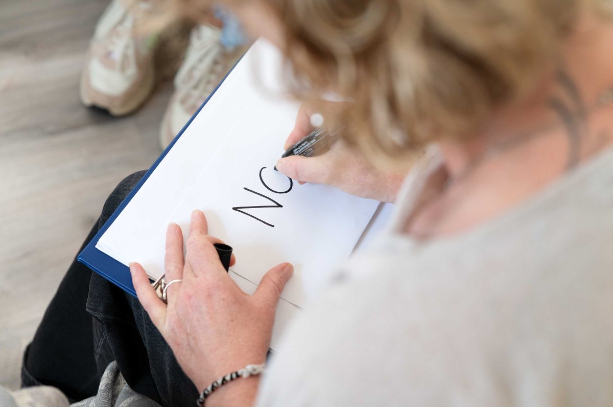 Atelier d’écriture – Expression personnelle en séance Participant écrivant sur un carnet lors d’un atelier animé par Pascale Dassonneville